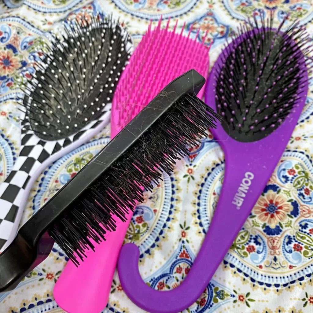 using a teasing brush to remove hair from brushes